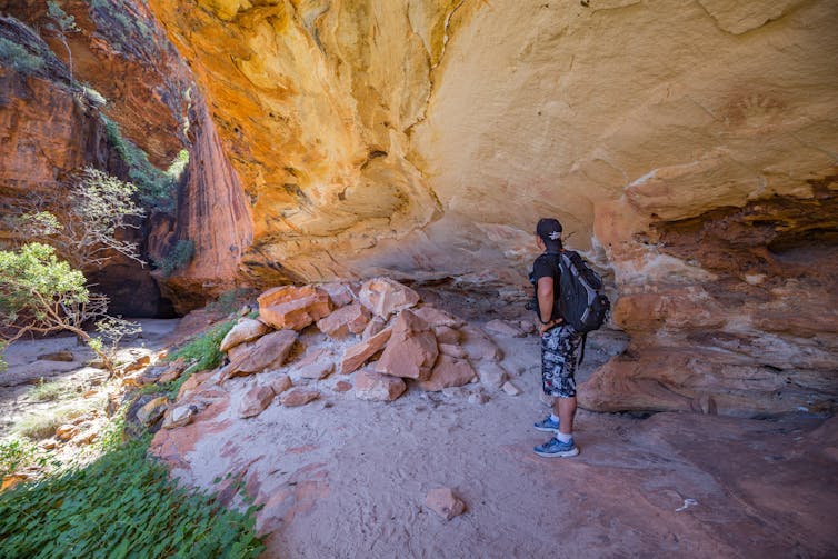 A hiker views an australian Indigenous art in a cave