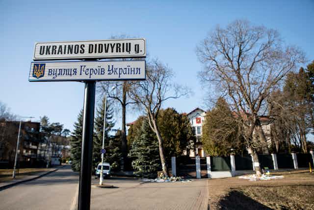 A sign post on a residential street sporting two street name signs in Cyrillic and Latin script.