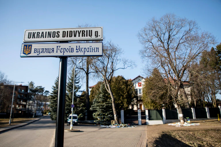 A sign post on a residential street sporting two street name signs in Cyrillic and Latin script.