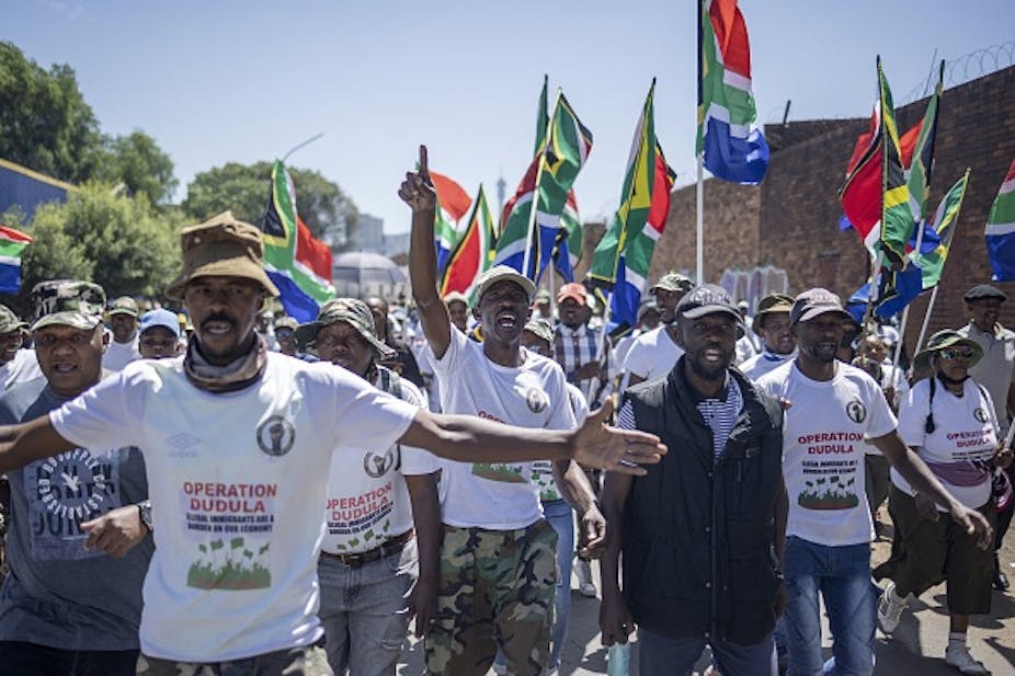 Men shout slogans and hoist South African flags as they down a street in the Johannesburg CBD. 