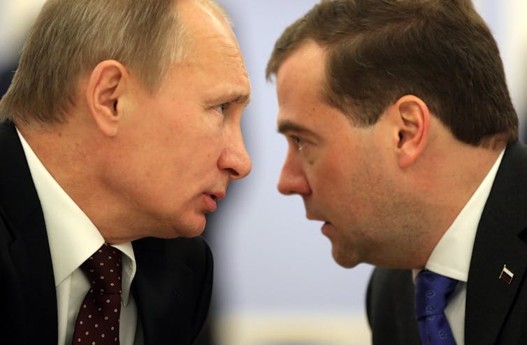 Vladimir Putin and his close ally Dmitri Medvedev with their heads together.