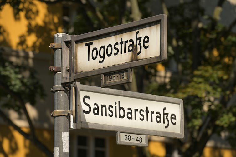 Two German street signs against a leafy background.