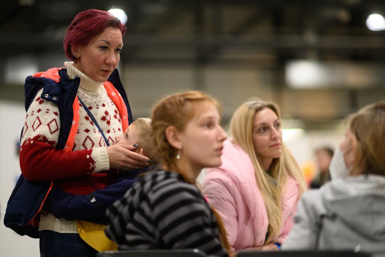 Three women sit and look to the right attentively.