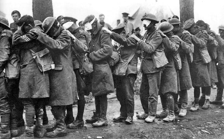 Des soldats aveuglés, yeux bandés, se tiennent en file indienne. Photo noir et blanc d’époque