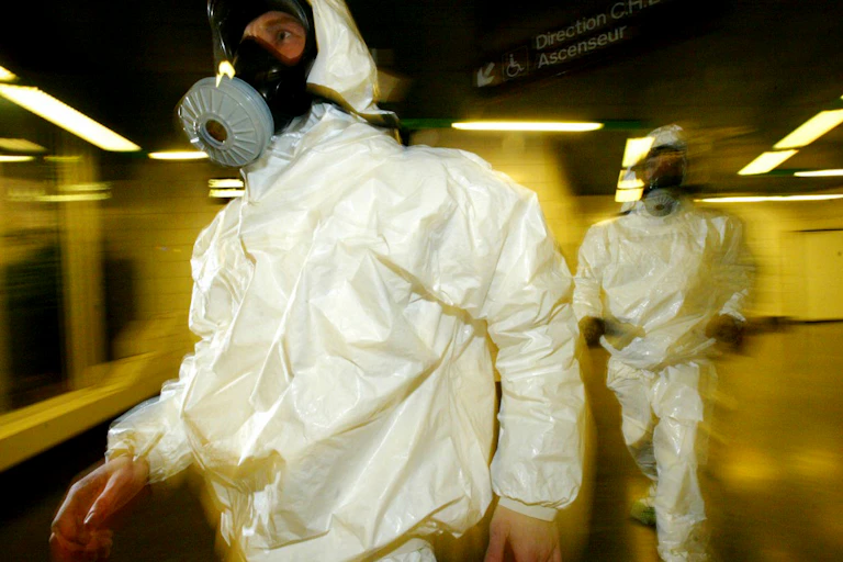Deux pompiers en tenue de protection blanche s'engouffrent dans le métro