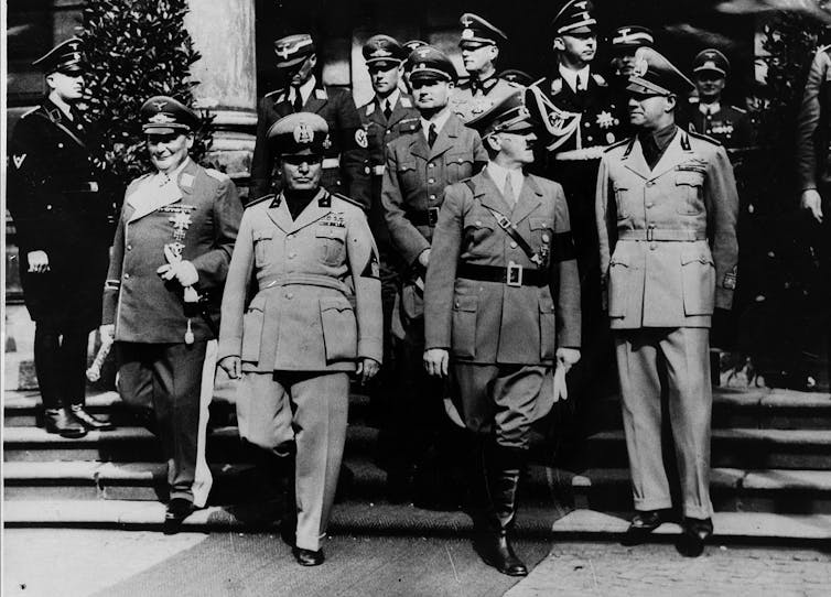 A black and white photo shows a group of men in military uniforms.