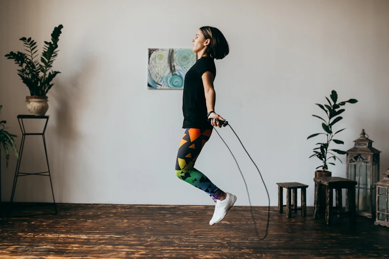A woman jumps rope in her house.