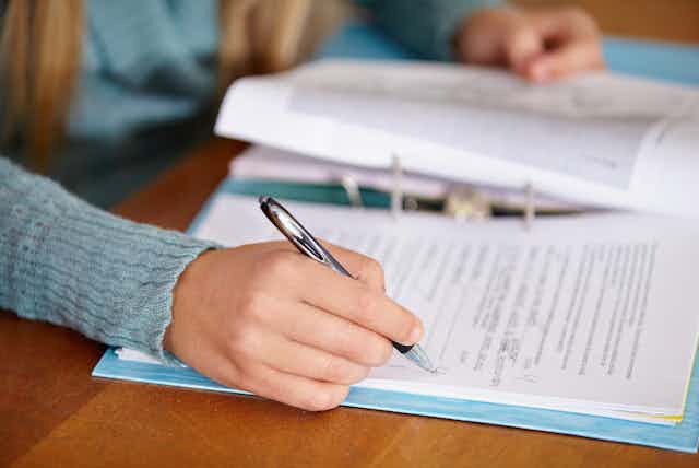 A person holding a pen marks pages in a binder