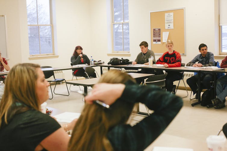 Young people sit around a table in a classroom