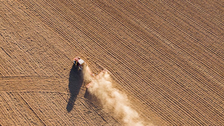 An aerial view of a tractor tilling land.