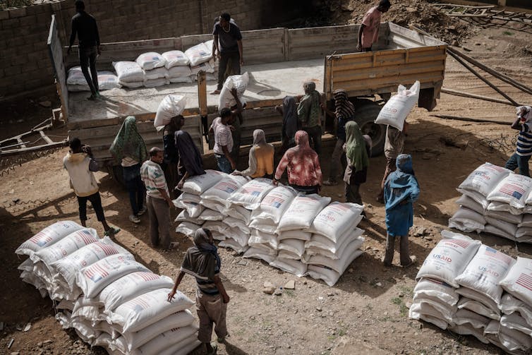 Workers unload sacks of wheat in an African village