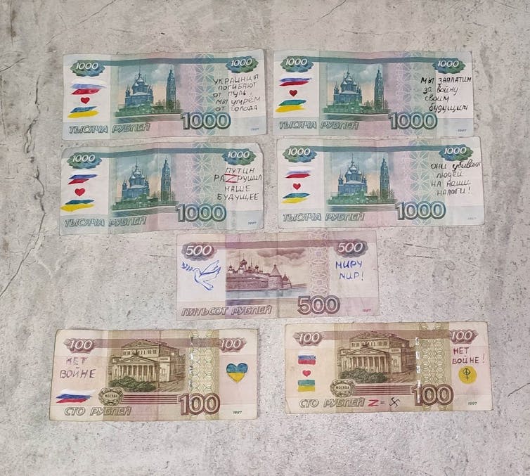 Rangées de billets de banque russes disposés sur une table, montrant des messages écrits à la main