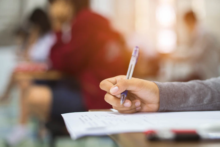 A hand seen holding a pen.