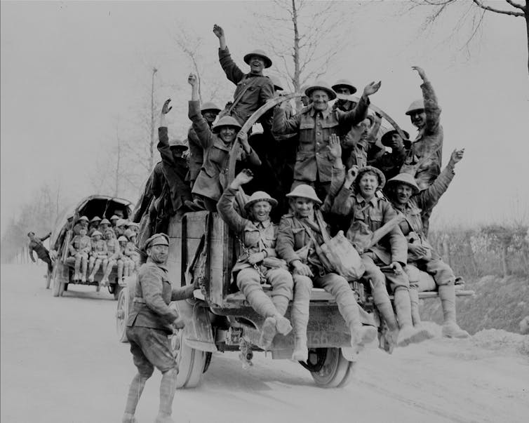 A black and white photo of men in uniform laughing and celebrating.