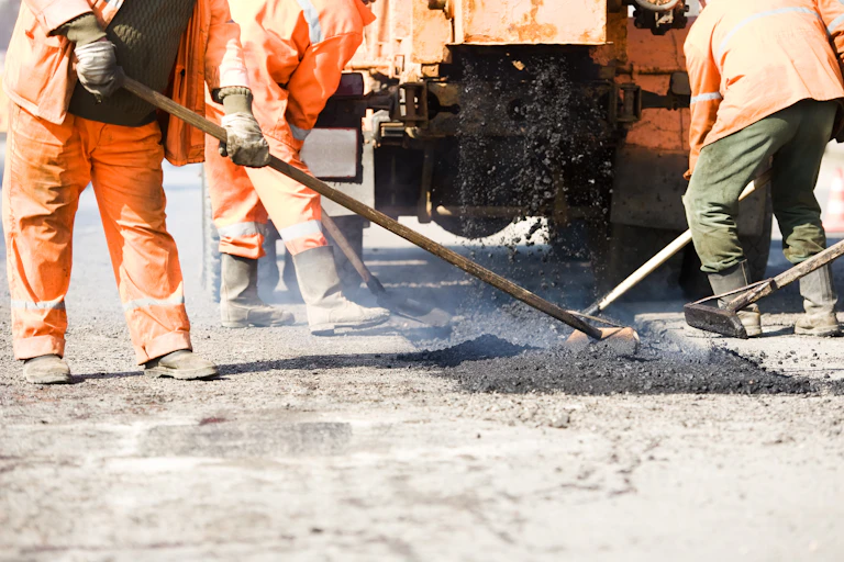 Road workers spreading bitumen