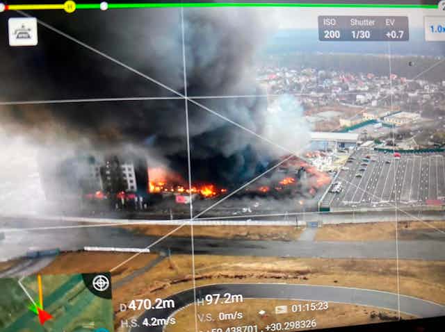An aerial view of a burning buildings overlaid with drone screen markings