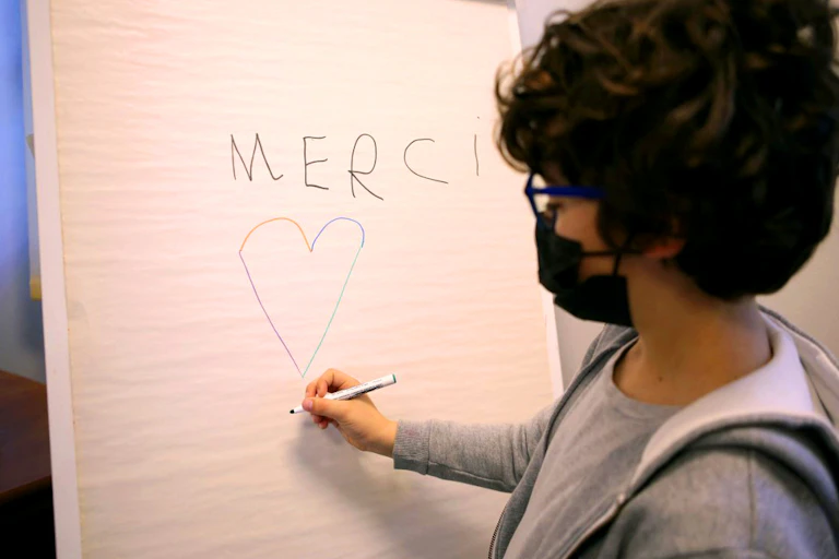 Un petit garçon, masqué, dessine un cœur après sa vaccination.