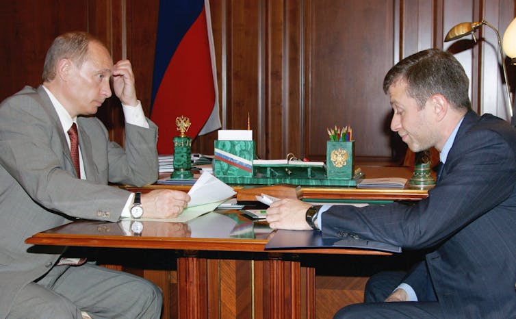 Vladimir Putin and Raoman Abramovich sit across a table form each other in 2005.