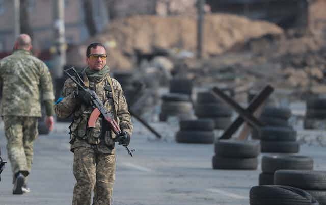 A Ukrainian soldier with a rifle at a roadblock in Kyiv.