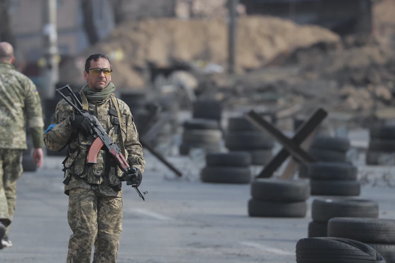 A Ukrainian soldier with a rifle at a roadblock in Kyiv.