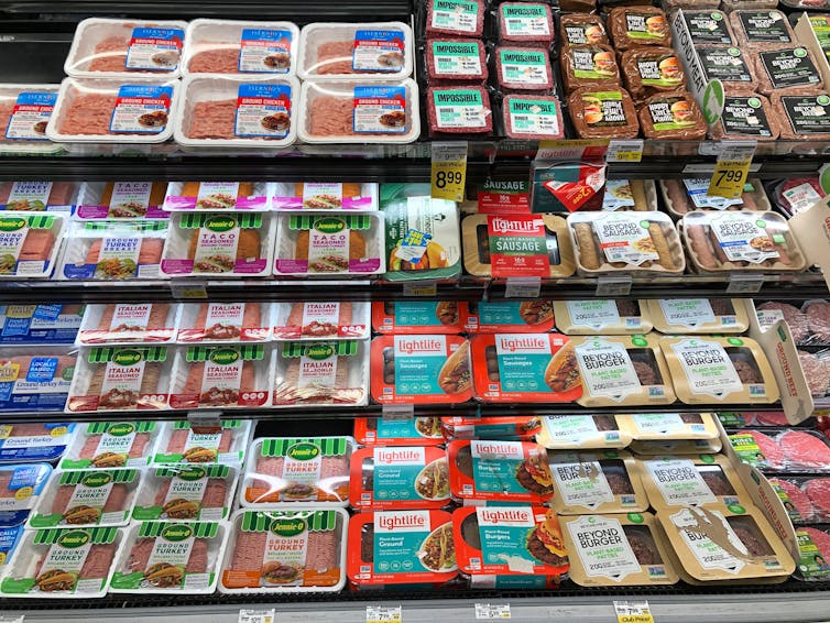 A refrigerator section in a supermarket with meat and plant-based meat alternatives.