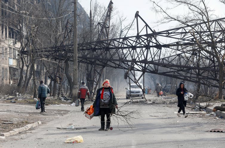 Woman walks in front of fallen electricity pylon