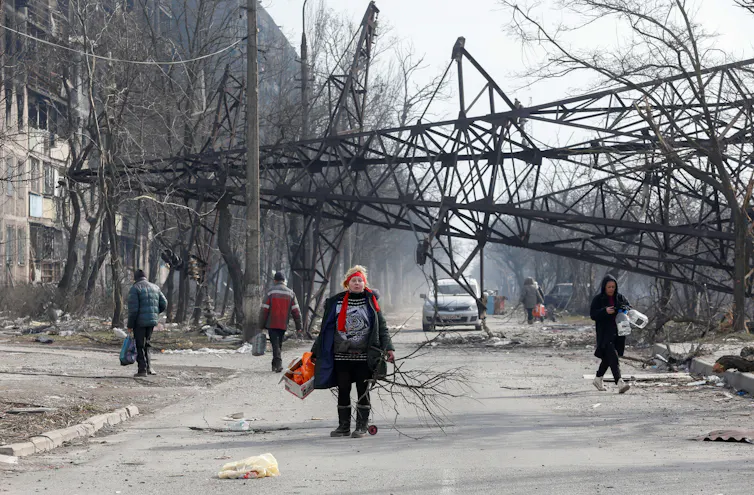 Woman walks in front of fallen electricity pylon