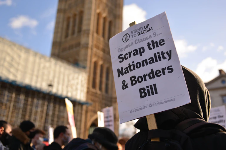 Hooded man holding sign.