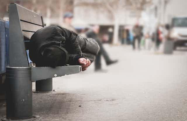 A man sleeping on a bench in an urban area