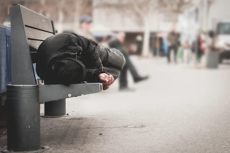 A man sleeping on a bench in an urban area
