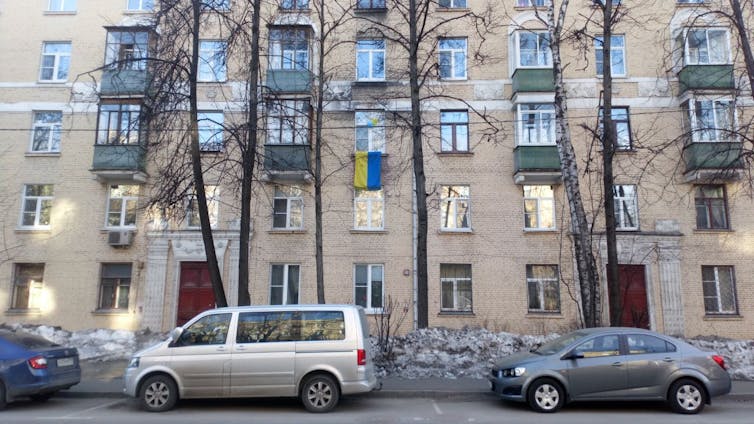 A Ukrainian flag striped with blue and yellow is seen hanging in an apartment window.