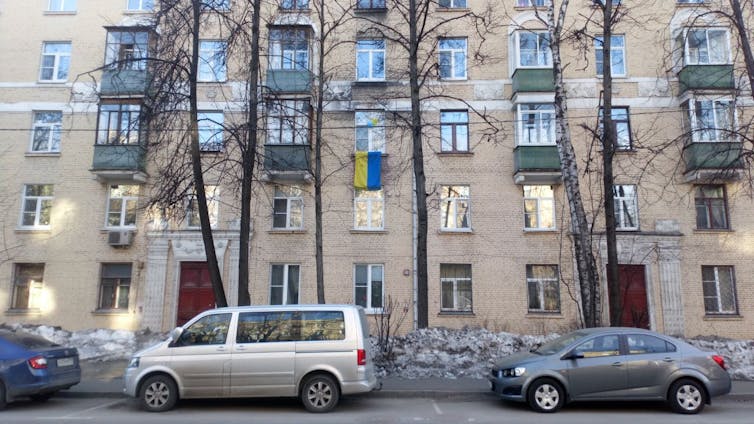 Un drapeau ukrainien rayé de bleu et de jaune est vu suspendu à la fenêtre d’un appartement