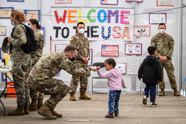A U.S. soldier stands in front of a sign that says