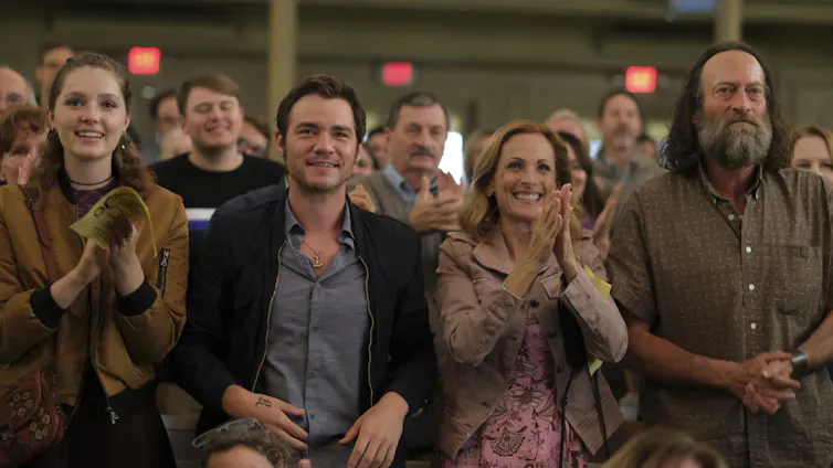 Four people seen in a row applauding.