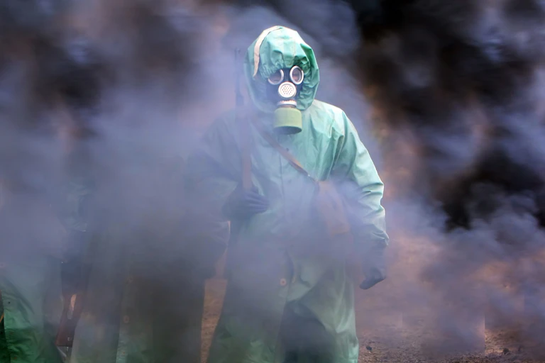 Soldado con traje de protección y máscara entre humo