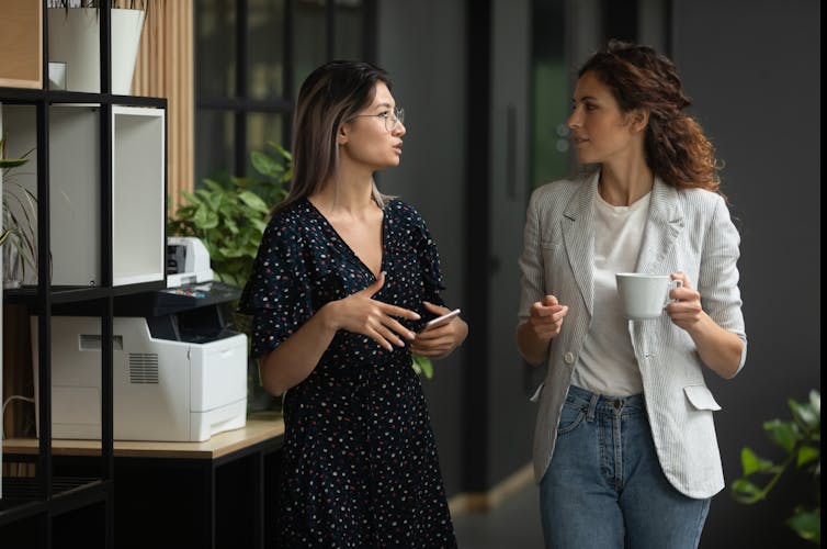 Two young women talking at work.