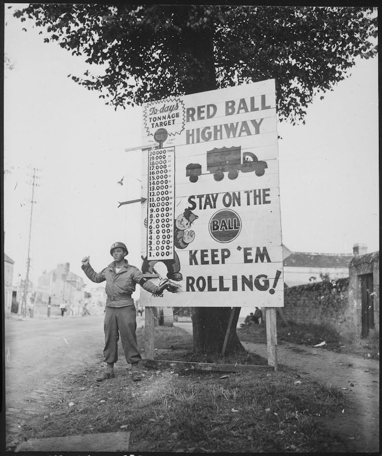 A Black solider stands near a sign that says Red Ball Highway.