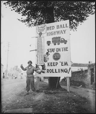 A Black solider stands near a sign that says Red Ball Highway.