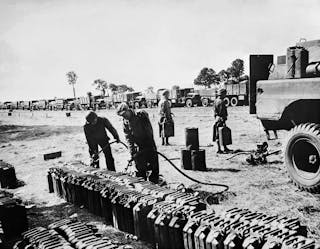 Black soldiers are seen filling up gasoline tanks for dozens of trucks used to transport military supplies.