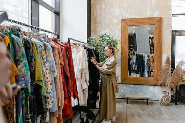 A woman looks at a rack of second-hand clothing