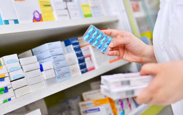 Pharmacist taking medicines off shelf