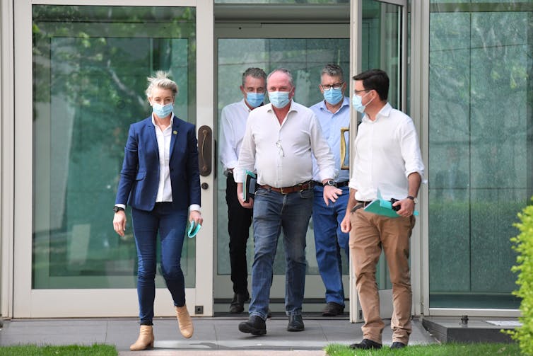 Four men and a woman exit glass doors