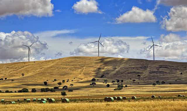 Three wind turbines on a brown hill 
