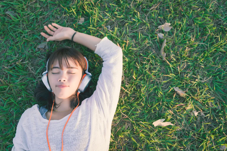 Woman laying on grass wearing headphones