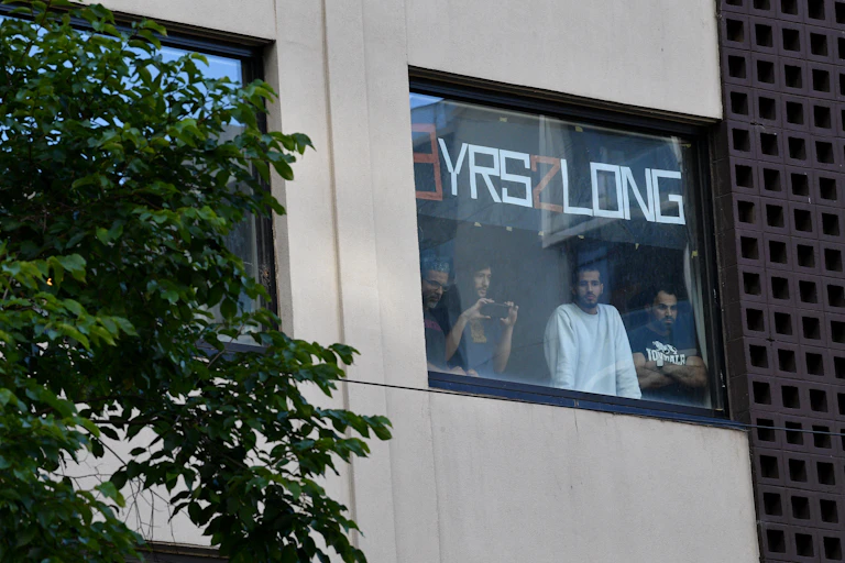 Detainees seen inside the Park Hotel in Melbourne holding a sign saying '8 years too long', January 2022