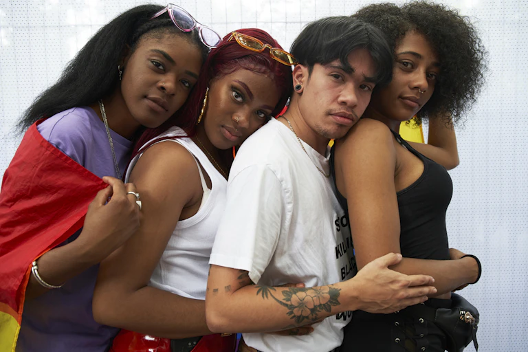 Four young trans people of color embracing each other front to back