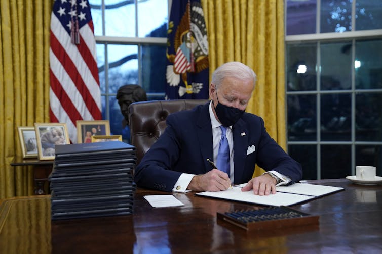 President Biden signing a document in the oval office.