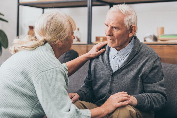 Confused elderly man being helped by his wife.