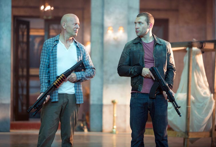 Bruce Willis on a film set with a gun.