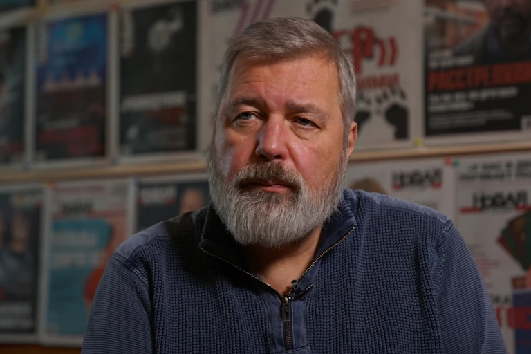 Dmitry Muratov a portrait shot against a backdrop of newspaper covers.